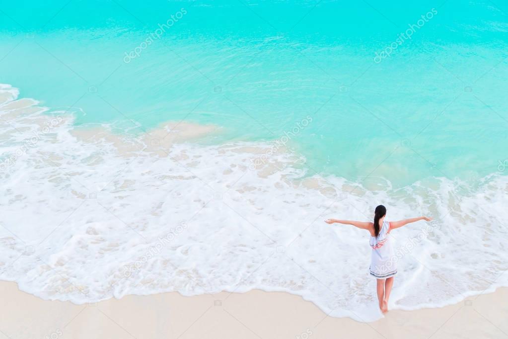 Happy girl at beach in shallow water with small waves. Top view of beautiful girl on the seashore