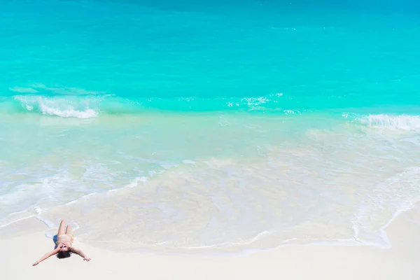 Bovenaanzicht van jong mooi meisje liggend op het strand in ondiep tropisch water aan de kust — Stockfoto