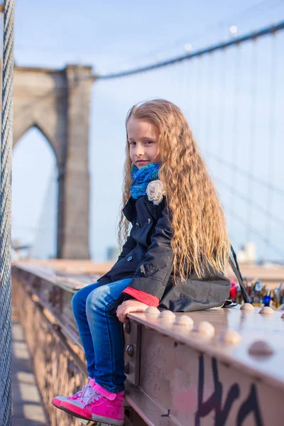 Schattig meisje zittend op Brooklyn Bridge met uitzicht op de weg — Stockfoto