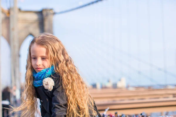 Adorable little girl sitting at Brooklyn Bridge with view on the road — Stock Photo, Image