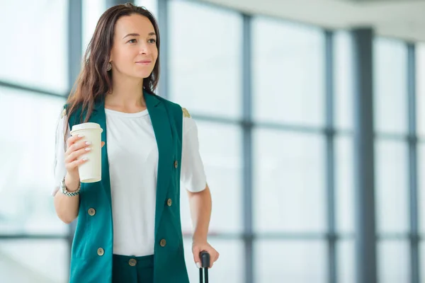 Jeune femme à l'aéroport international marchant avec ses bagages et café à emporter — Photo