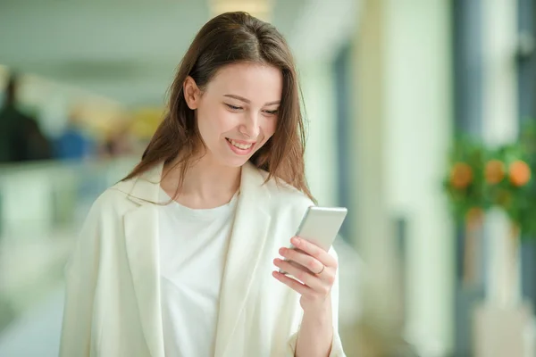 Portrait de jeune femme avec smartphone à l'aéroport international. Passager d'une compagnie aérienne dans un salon d'aéroport en attente d'un avion — Photo