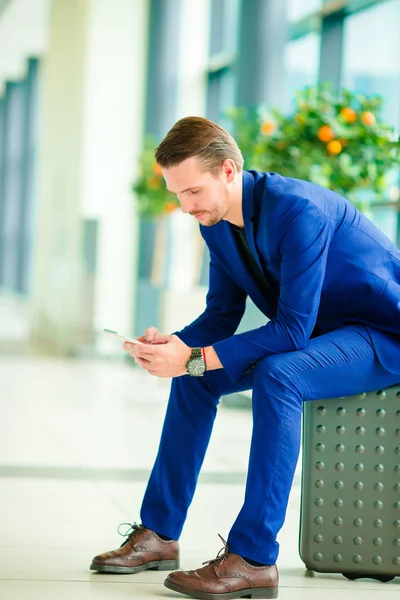 Joven con teléfono inteligente en el aeropuerto. Hombre caucásico con teléfono celular en el aeropuerto mientras espera el embarque — Foto de Stock