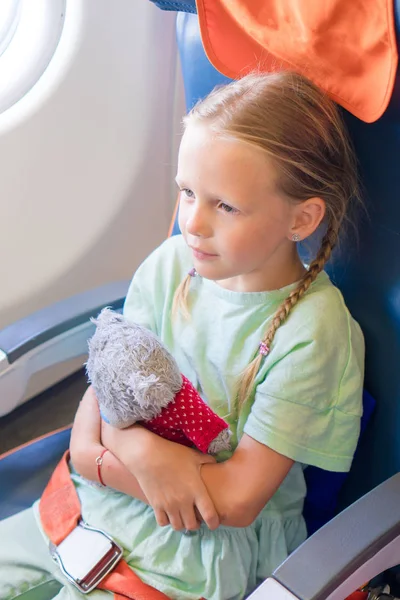 Sevimli küçük kız bir uçakla seyahat. Uçak pencere oturan çocuk — Stok fotoğraf
