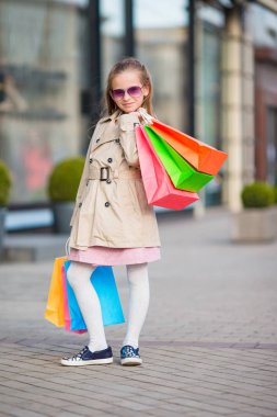 Sevimli küçük kız alışveriş torbaları ile yürüme. Moda yürümeye başlayan çocuk Avrupa şehri açık havada