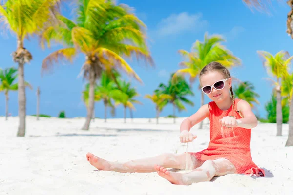 小さな女の子は、ヤシの木立で熱帯の休暇中にビーチで遊ぶ — ストック写真