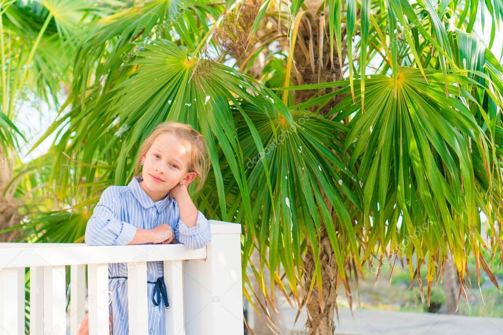 Little adorable girl on a wooden bridge on their way to a white tropical beach and turquoise ocean