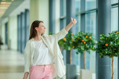 Genç kadın yanında smartphone uluslararası havaalanında uçuş için bekleyen seldie alarak