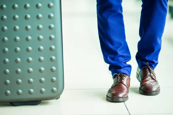Közeli kép: férfi cipő-és csomagtér a repülőtéren. Fiatal turista ember repülőtéren kész részére utazótáska — Stock Fotó