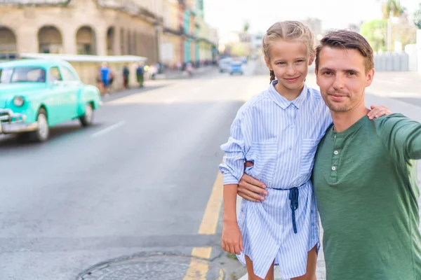 Familj av pappa och lilla flickan tar selfie i populärt område i Gamla Havanna, Kuba. Lite barn och unga far utomhus på en gata i Havanna — Stockfoto