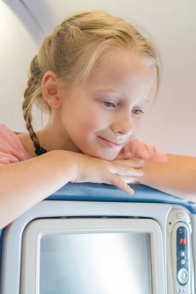 Adorable niña viajando en un avión y sonriendo —  Fotos de Stock