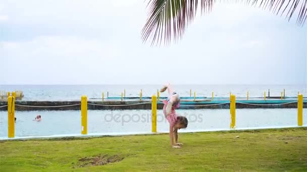 Menina ativa na praia se divertindo muito. Miúdo desportivo faz a roda na praia — Vídeo de Stock