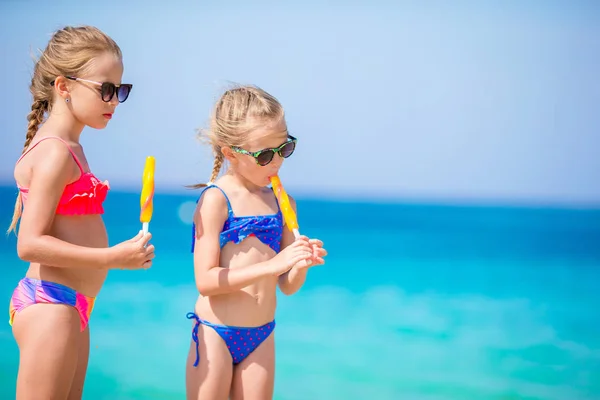 Szczęśliwe dziewczynki jedzące lody podczas wakacji na plaży. Ludzie, dzieci, przyjaciele i koncepcja przyjaźni — Zdjęcie stockowe