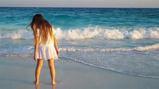 Очаровательная счастливая маленькая девочка на белом пляже на закате — стоковое видео