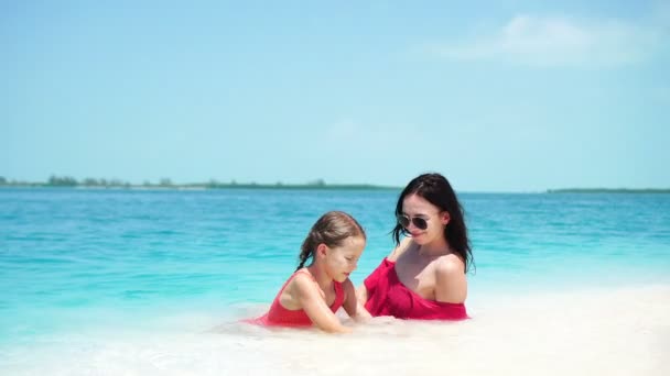 少しかわいい女の子と若い母親は白の上に横たわる熱帯のビーチでビーチ、夏の休暇を楽しむ — ストック動画