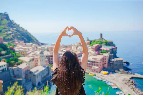 Beautiful girl making with hands heart shape on the old coastal town background of Vernazza, Cinque Terre National Park, Liguria, Italy, Europe — стоковое фото