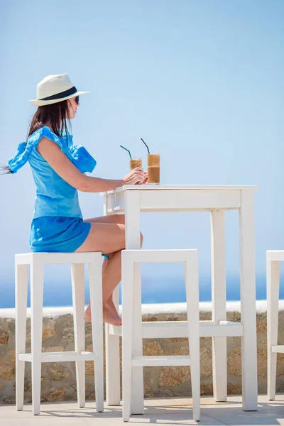 Chica joven bebiendo café frío disfrutando de vistas al mar. Hermosa mujer relajarse durante vacaciones exóticas en la playa disfrutando de frappe — Foto de Stock