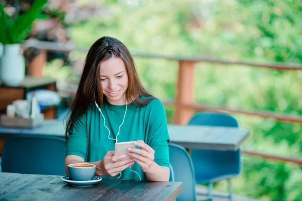 Jonge vrouw met cel telefoon zittend alleen in koffie shop tijdens de vrije tijd — Stockfoto