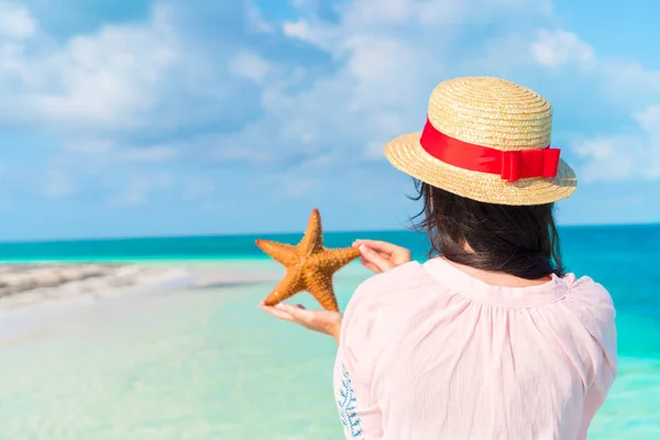 Glad ung kvinna med sjöstjärnor på vita stranden i naturreservatet — Stockfoto