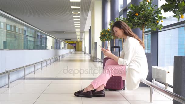 Jonge vrouw met smartphone in internationale luchthaven vlucht wacht — Stockvideo