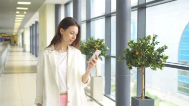 Uluslararası havaalanında smartphone ile turist kız. Havayolu Yolcu uçuş uçak için bekleyen bir Havaalanı Lounge