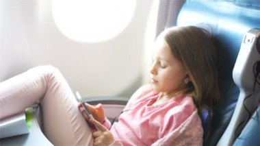 Sevimli küçük kız bir uçakla seyahat. Uçak penceresinde yakınındaki dizüstü bilgisayar ile şirin çocuk