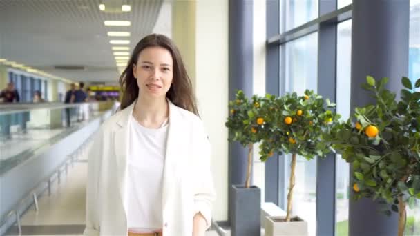 Jonge vrouw met bagage op de internationale luchthaven loopt met haar bagage. Passagier van een luchtvaartmaatschappij in een luchthavenlounge die wacht op een vliegtuig. — Stockvideo