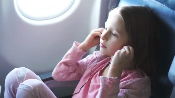 Bedårande liten flicka reser med ett flygplan. Söta unge Titta filmen nära fönster i flygplan. Slow Motion — Stockvideo