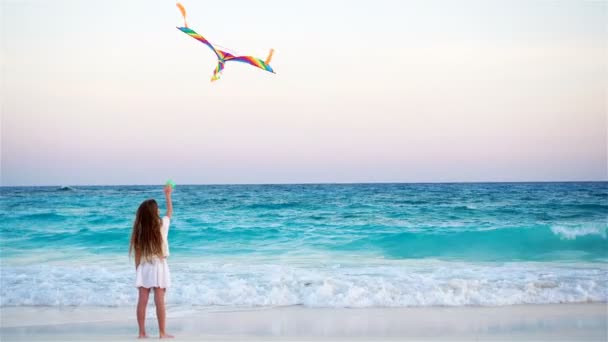 Little girl with flying kite on tropical beach at sunset. Kid play on ocean shore. Child with beach toys. — Stock Video