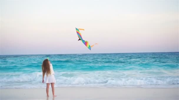 Little girl with flying kite on tropical beach at sunset. Kid play on ocean shore. Child with beach toys. — Stock Video