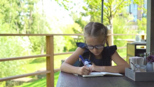 Adorable little school girl with notes and pencils outdoor. Back to school. — Stock Video