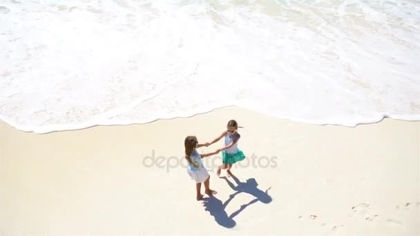 Crianças adoráveis brincam juntas na praia em águas rasas.Vista de cima da praia deserta com água azul-turquesa — Vídeo de Stock