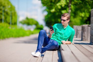 Genç adam açık havada parkta smartphone ile adam hareket eden smartphone kullanarak.