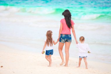 Sevimli küçük kızlar ve beyaz sahilde genç bir anne.