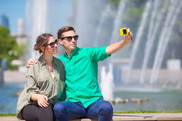 Paar nemen een selfie achtergrond de fontein. Jonge man die foto van de vrouw op de straat lachen en plezier in de zomer. — Stockfoto