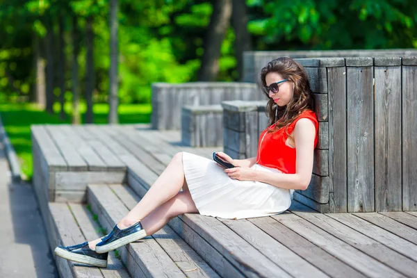 Mooi meisje luisteren muziek door smartphone op zomervakantie. Jonge aantrekkelijke toeristische met mobiele telefoon buitenshuis genieten van vakantie. — Stockfoto
