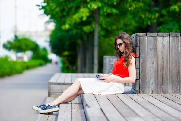 Belle fille écoutant de la musique par smartphone pendant les vacances d'été. Jeune touriste attrayant avec téléphone portable en plein air profiter des vacances . — Photo