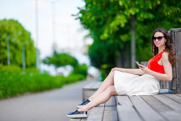 Belle fille écoutant de la musique par smartphone pendant les vacances d'été. Jeune touriste attrayant avec téléphone portable en plein air profiter des vacances . — Photo