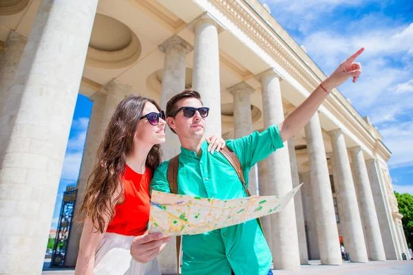 Jóvenes amigos turistas que viajan de vacaciones en Europa sonriendo felices. Familia caucásica con mapa de la ciudad en busca de atracciones — Foto de Stock