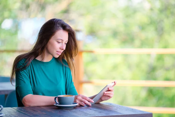 Jeune femme avec smartphone assis seul dans un café extérieur — Photo