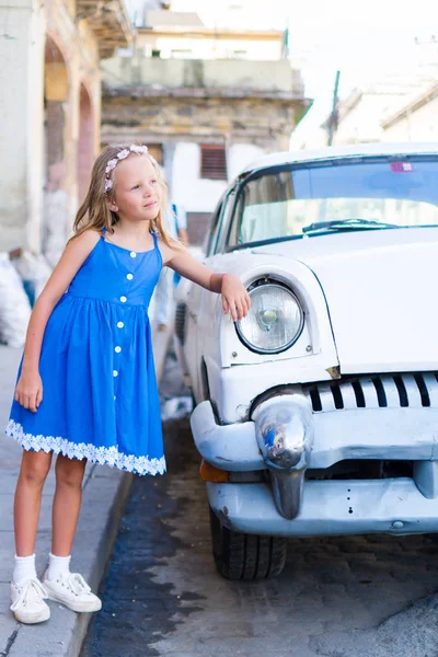 Entzückendes kleines Mädchen in beliebter Gegend im alten Havanna, Kuba. Porträt von Kind Hintergrund Oldtimer-amerikanisches Auto — Stockfoto