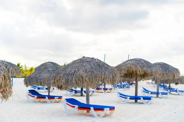 Exotiska tropiska tom sandstrand med parasoller och liggstolar för strand omgiven av palmer — Stockfoto