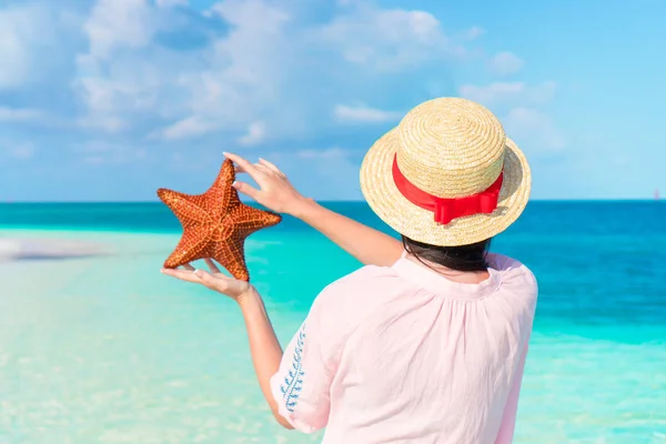 Back view of woman with starfish in hands on white beach in the nature reserve — Stock Photo, Image