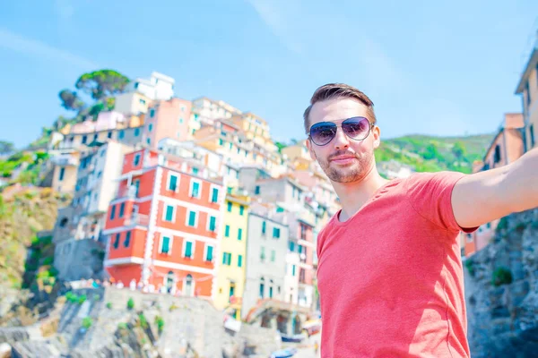 Joven tomando selfie con hermosa vista en el antiguo pueblo italiano Riomaggiore, Cinque Terre, Liguria, Italia. Vacaciones italianas europeas . —  Fotos de Stock