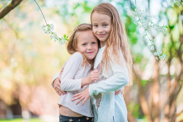Underbara små flickor i blommande äppelträdsträdgård på vårdagen — Stockfoto