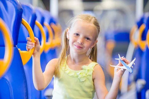 Adorable niña viajando en tren y divertirse con el modelo de avión en las manos —  Fotos de Stock