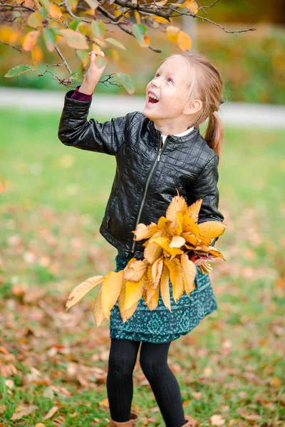 Portret uroczej dziewczynki z żółtymi i pomarańczowymi liśćmi bukiet na świeżym powietrzu w piękny jesienny dzień — Zdjęcie stockowe