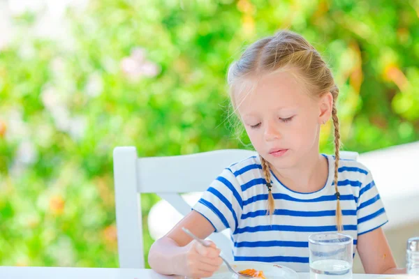 Niña adorable desayunando en la cafetería con vista al mar temprano en la mañana —  Fotos de Stock