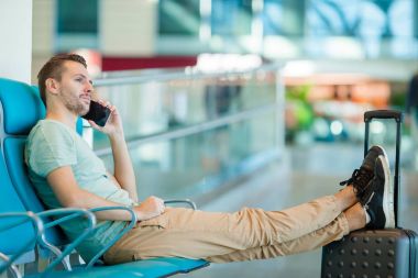 Uçuş uçak için bekleyen bir Havaalanı lounge genç adam. Beyaz adam akıllı telefon kapalı
