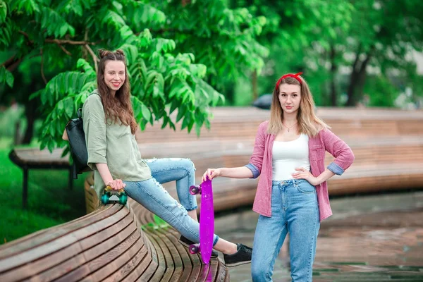 Two hipster girls with skateboard outdoors in the park. Active sporty women having fun together in skate park. — Stock Photo, Image